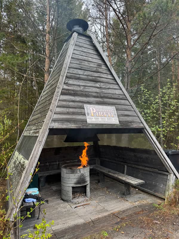 Den timrade grillkåtan i skogen med elden brinnande inuti