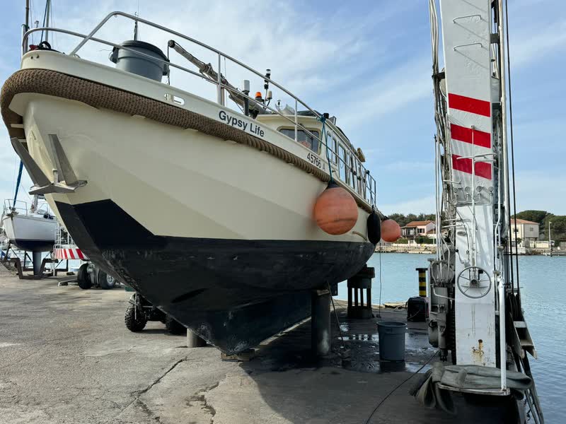 The Gypsy Life standing on blocks on the quay with the travel lift alongside